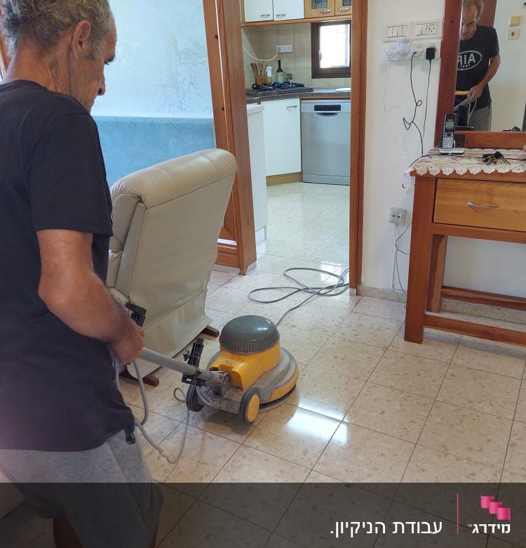 אדם מנקה רצפה עם מכונת פוליש חשמלית
